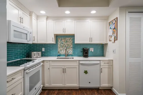 a kitchen with white cabinets and white appliances