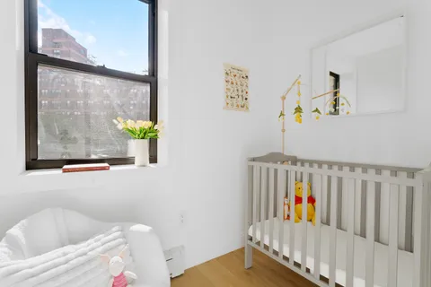 a view of a bedroom with baby crib and furniture
