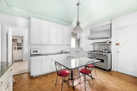 a kitchen with stainless steel appliances kitchen island granite countertop a sink a stove a refrigerator and white cabinets