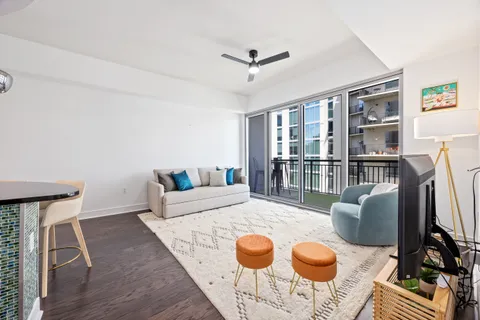 a living room with furniture a rug and a floor to ceiling window