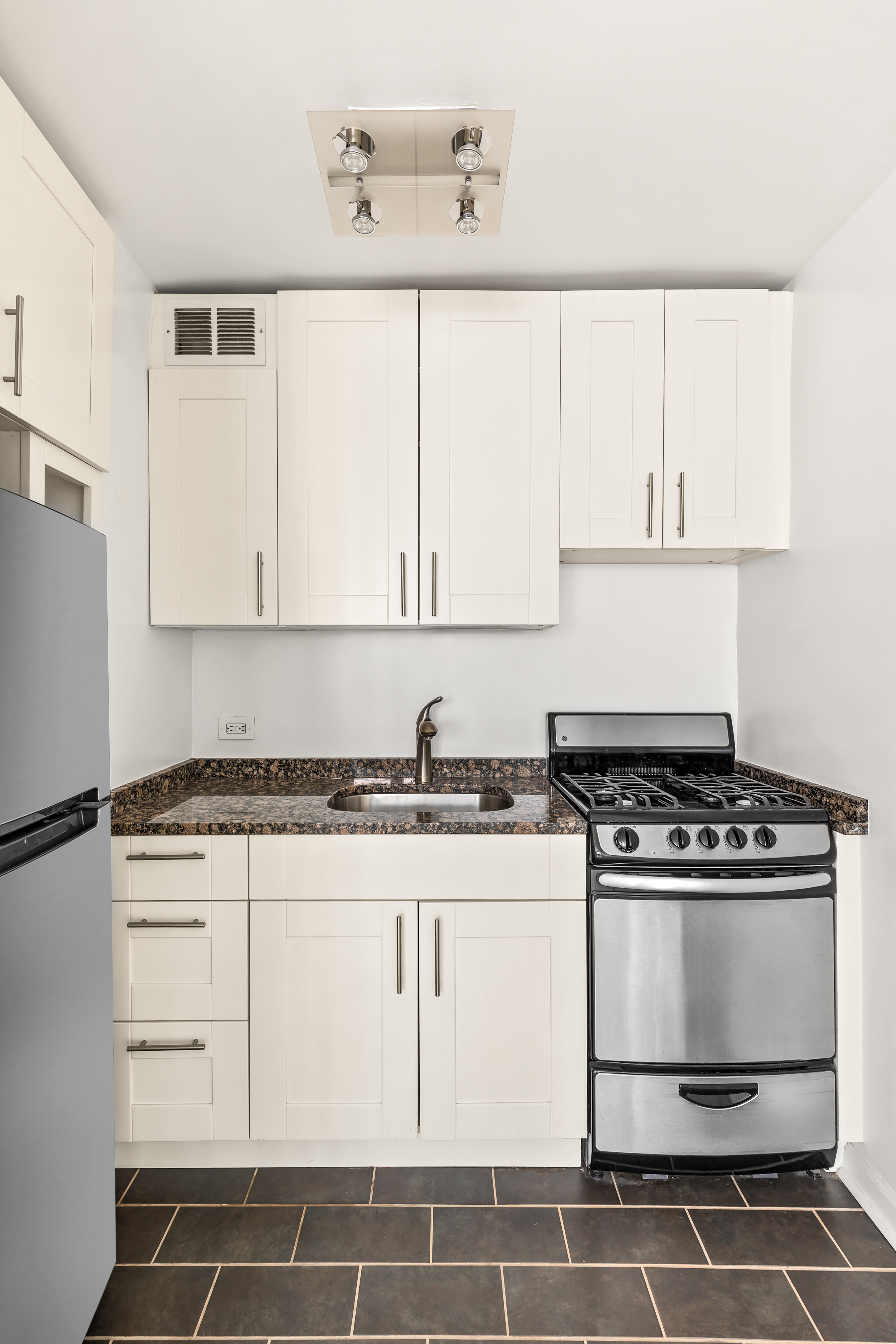 315 East 70th Street, Unit 4C Manhattan, NY 10021 - Photo 2 of 6 a kitchen with granite countertop white cabinets and white stove