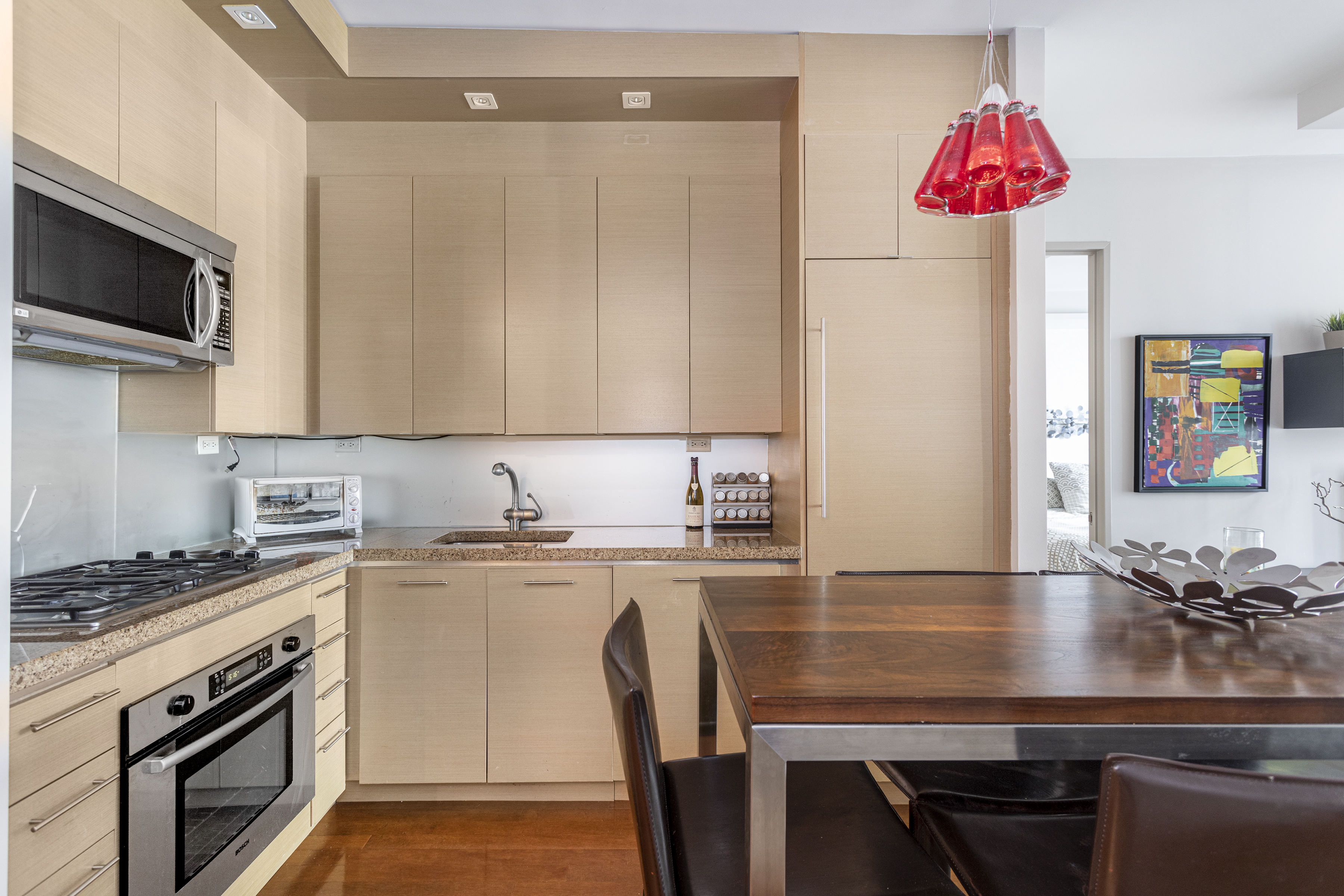 1600 Broadway, Unit 18G Manhattan, NY 10019 - Photo 2 of 10 a kitchen with stainless steel appliances kitchen island granite countertop a stove a sink and a microwave