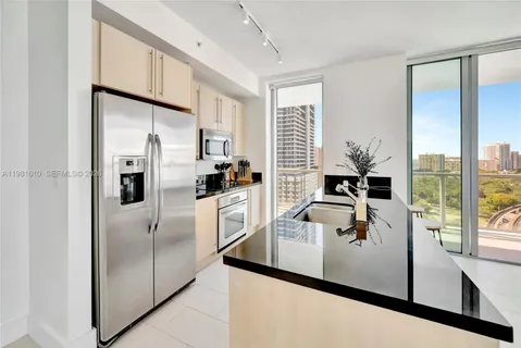 a kitchen with stainless steel appliances a refrigerator a sink and white cabinets