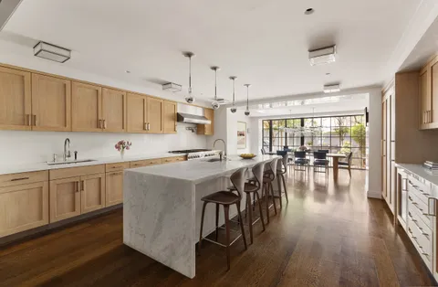 a kitchen with stainless steel appliances granite countertop a stove a refrigerator a kitchen island a dining table and chairs with wooden floor