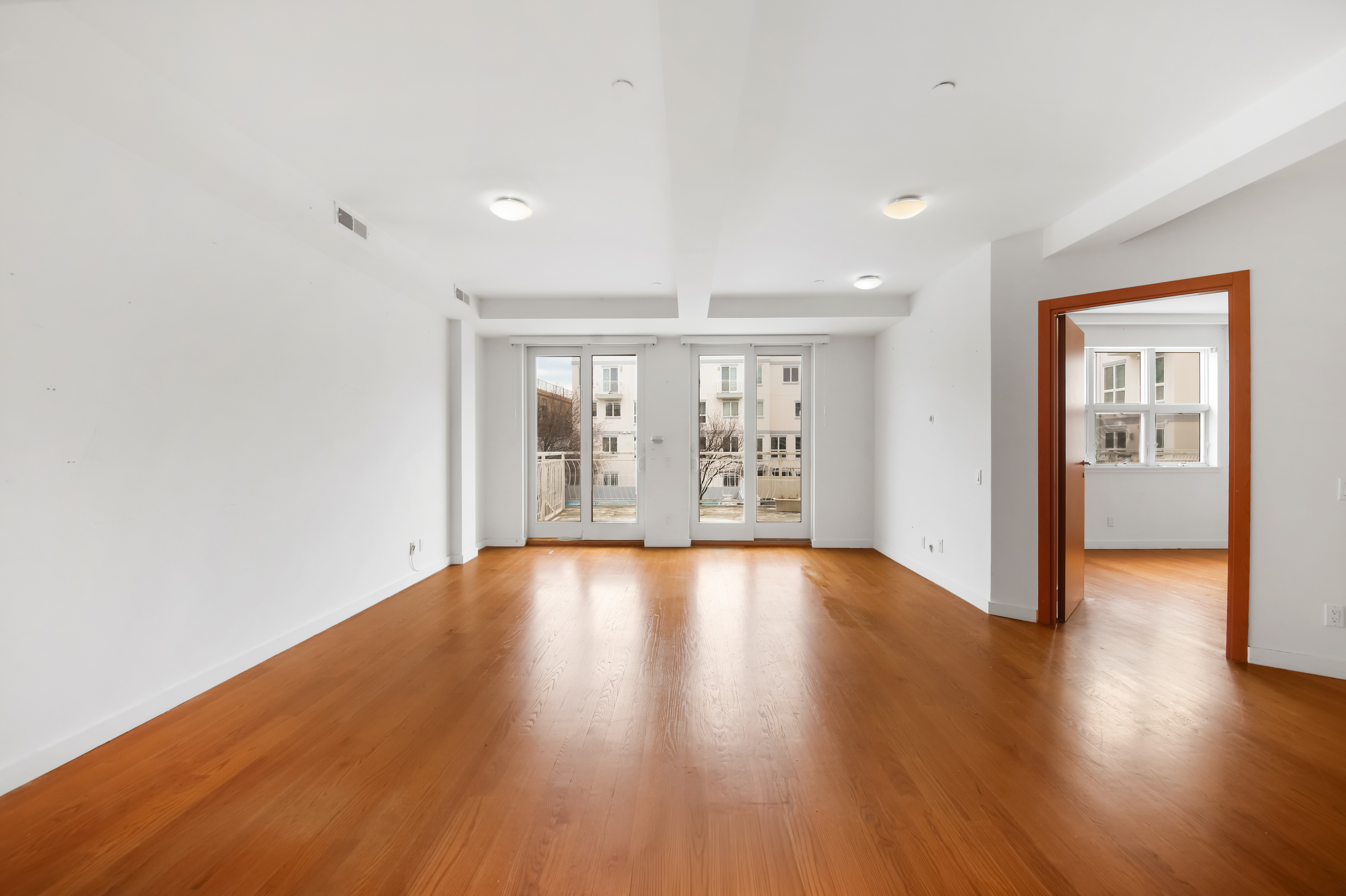 3112 Emmons Avenue, Unit 107 Brooklyn, NY 11235 - Photo 4 of 14 a view of an empty room with wooden floor and a window