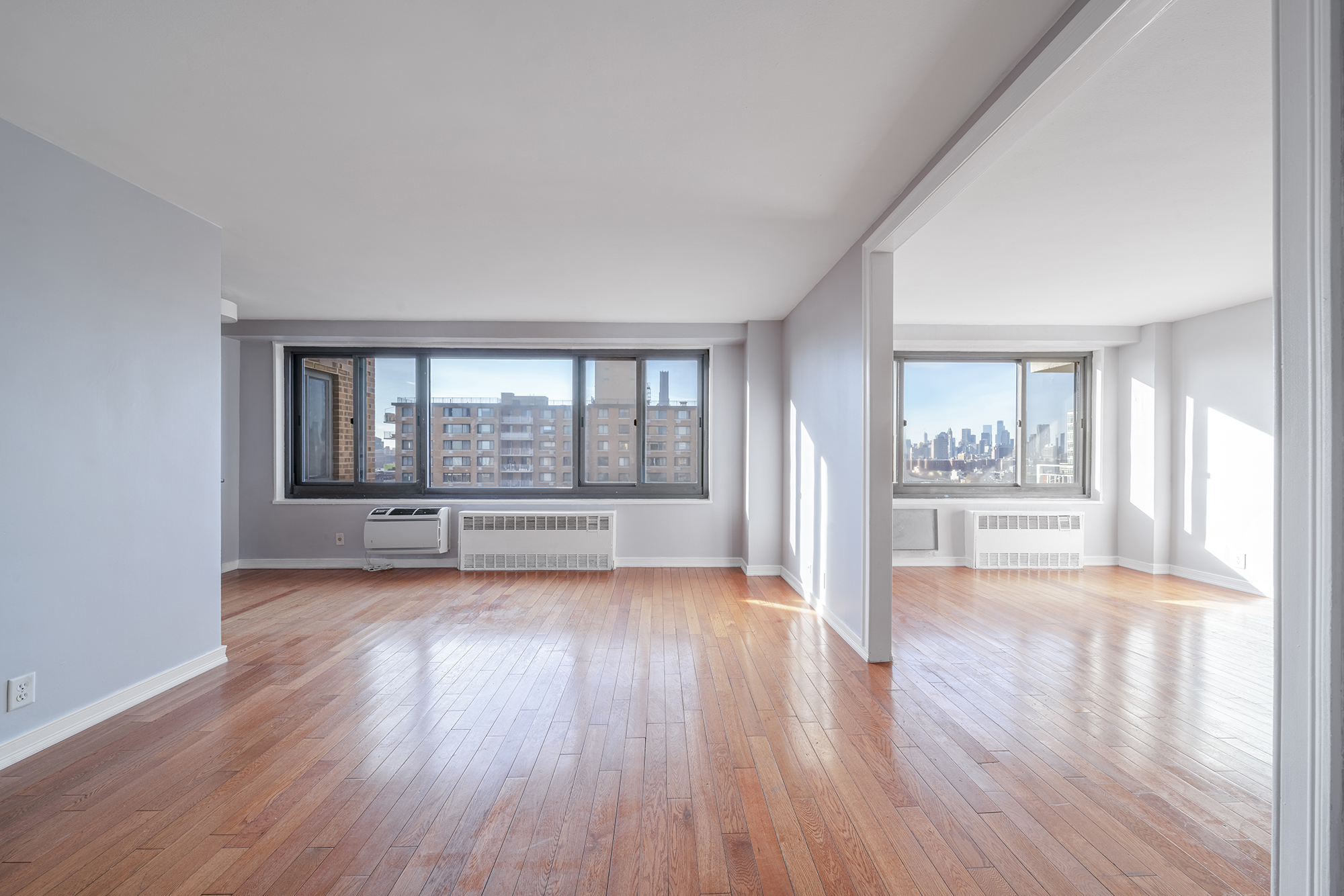 195 Willoughby Avenue, Unit 1517 Brooklyn, NY 11205 - Photo 2 of 4 a view of an empty room with wooden floor and a window