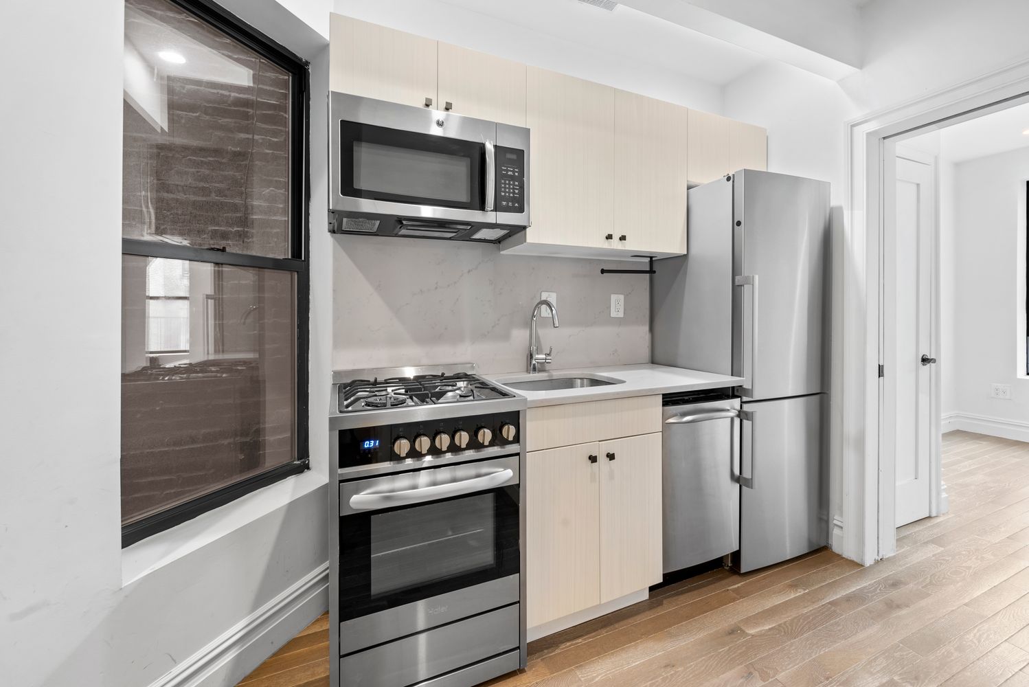 142 Sullivan Street, Unit 14 Manhattan, NY 10012 - Photo 4 of 10 a kitchen with stainless steel appliances a refrigerator stove and microwave