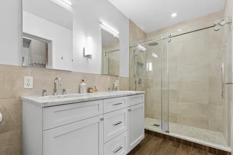 a bathroom with a shower sink vanity and mirror