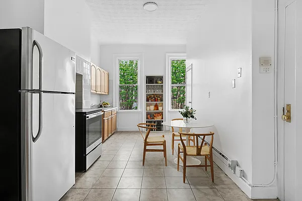 241 Himrod Street, Unit 3L Brooklyn, NY 11237 - Photo 2 of 5 a kitchen with a refrigerator a table and chairs in it