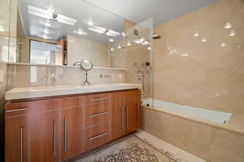 a bathroom with a double vanity sink a toilet a mirror and shower