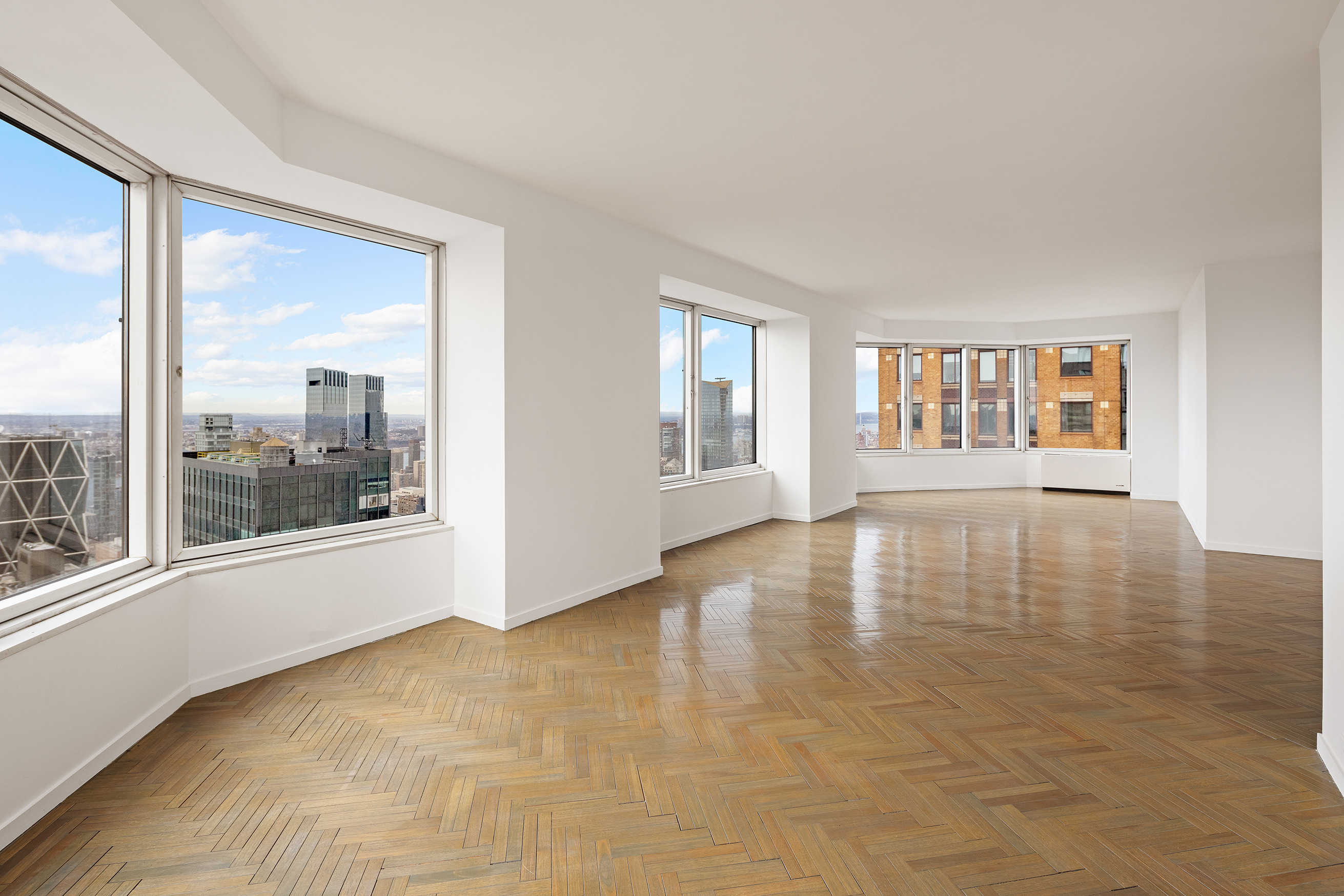 150 West 56th Street, Unit 6204 Manhattan, NY 10019 - Photo 4 of 15 a view of empty room with wooden floor and fan