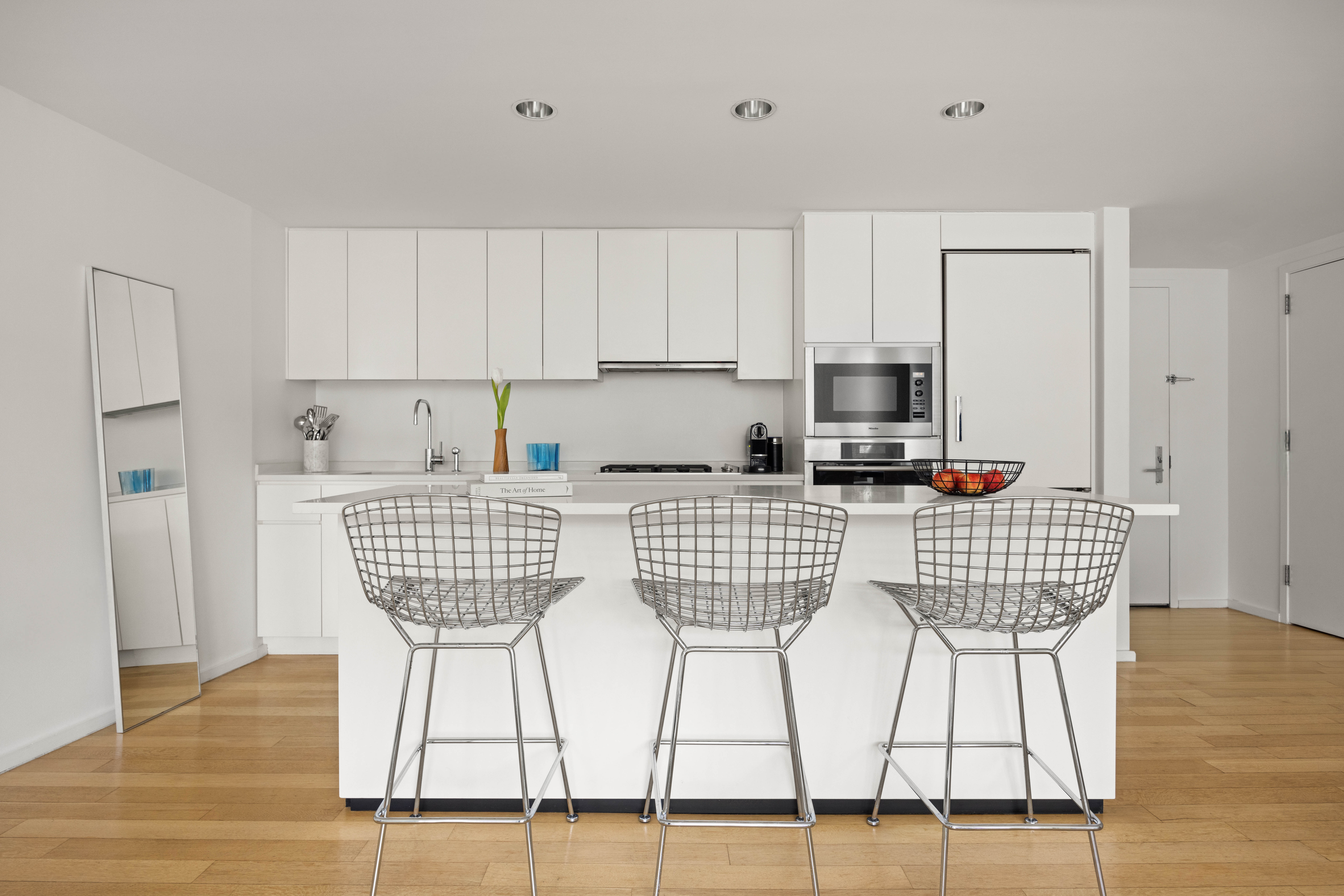 425 West 53rd Street, Unit 604 Manhattan, NY 10019 - Photo 5 of 12 a kitchen with stainless steel appliances kitchen island granite countertop a dining table chairs and a refrigerator