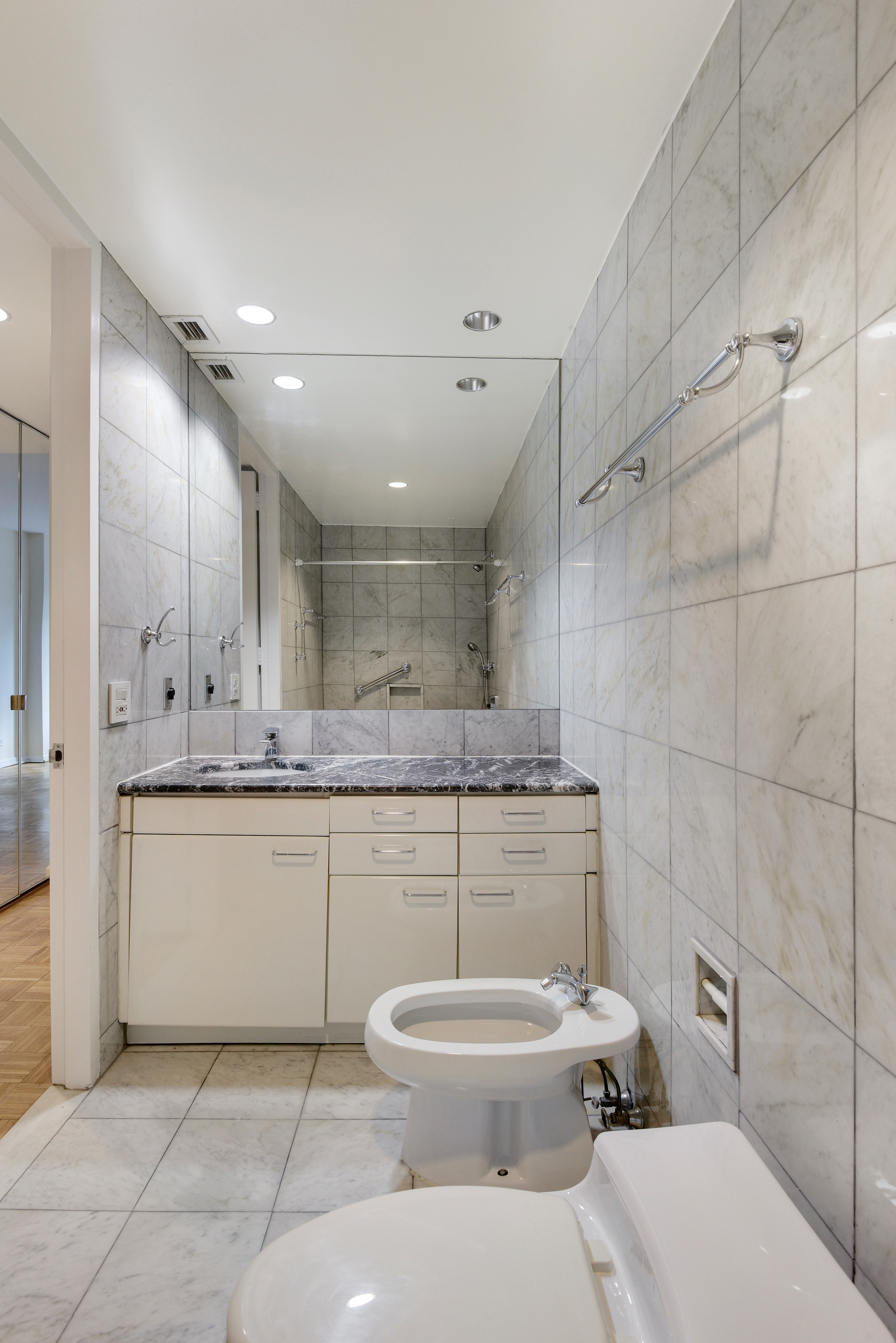 146 West 57th Street, Unit 38E Manhattan, NY 10019 - Photo 7 of 16 a bathroom with a toilet sink and mirror