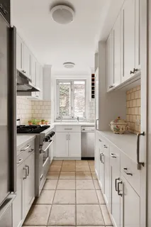 a kitchen with stainless steel appliances granite countertop a stove a sink and white cabinets