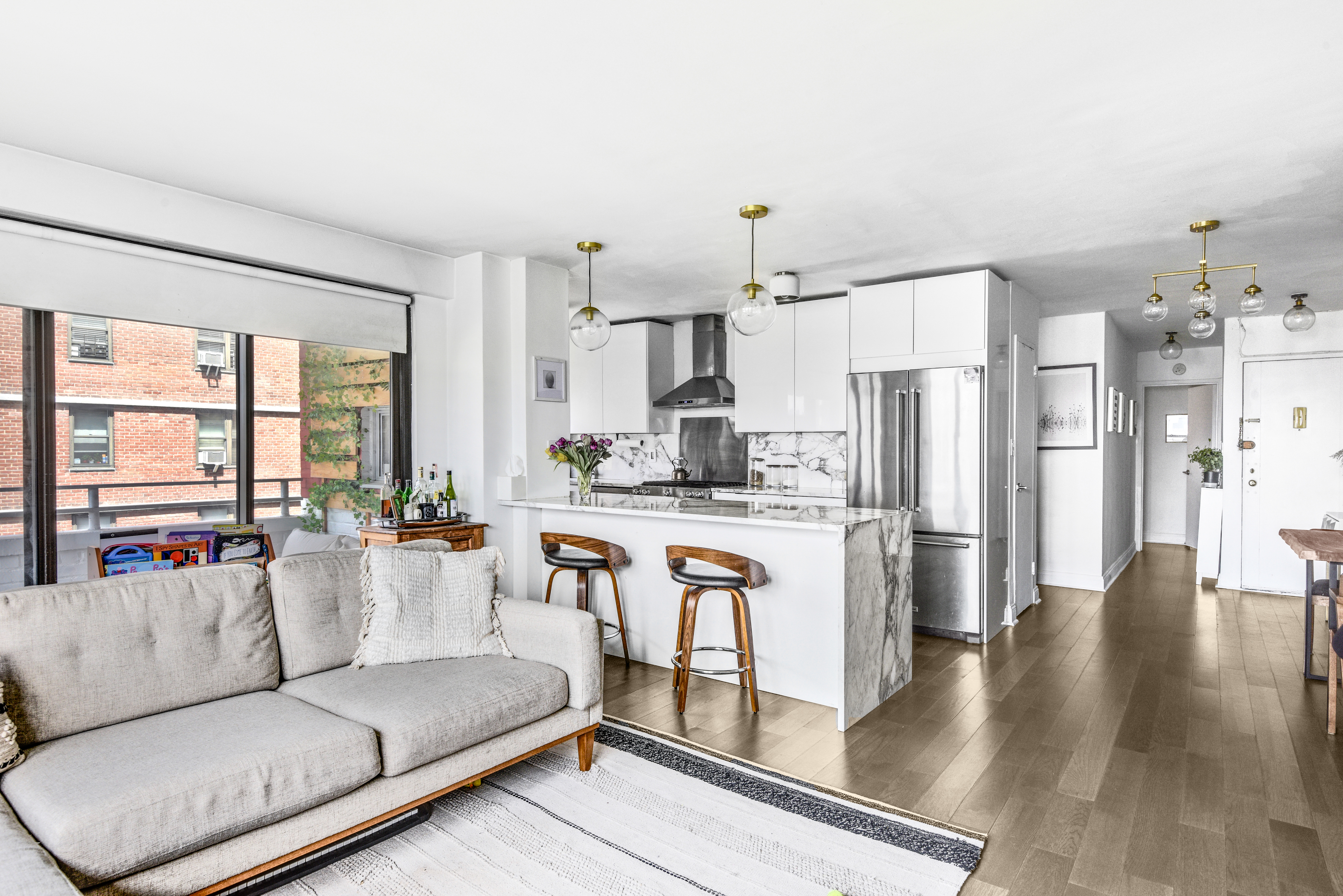 208 East Broadway, Unit J1304 Manhattan, NY 10002 - Photo 3 of 19 a living room with stainless steel appliances kitchen island granite countertop a refrigerator and a stove top oven