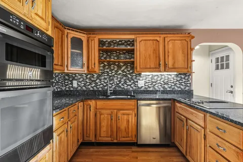 a kitchen with granite countertop stainless steel appliances a sink and cabinets