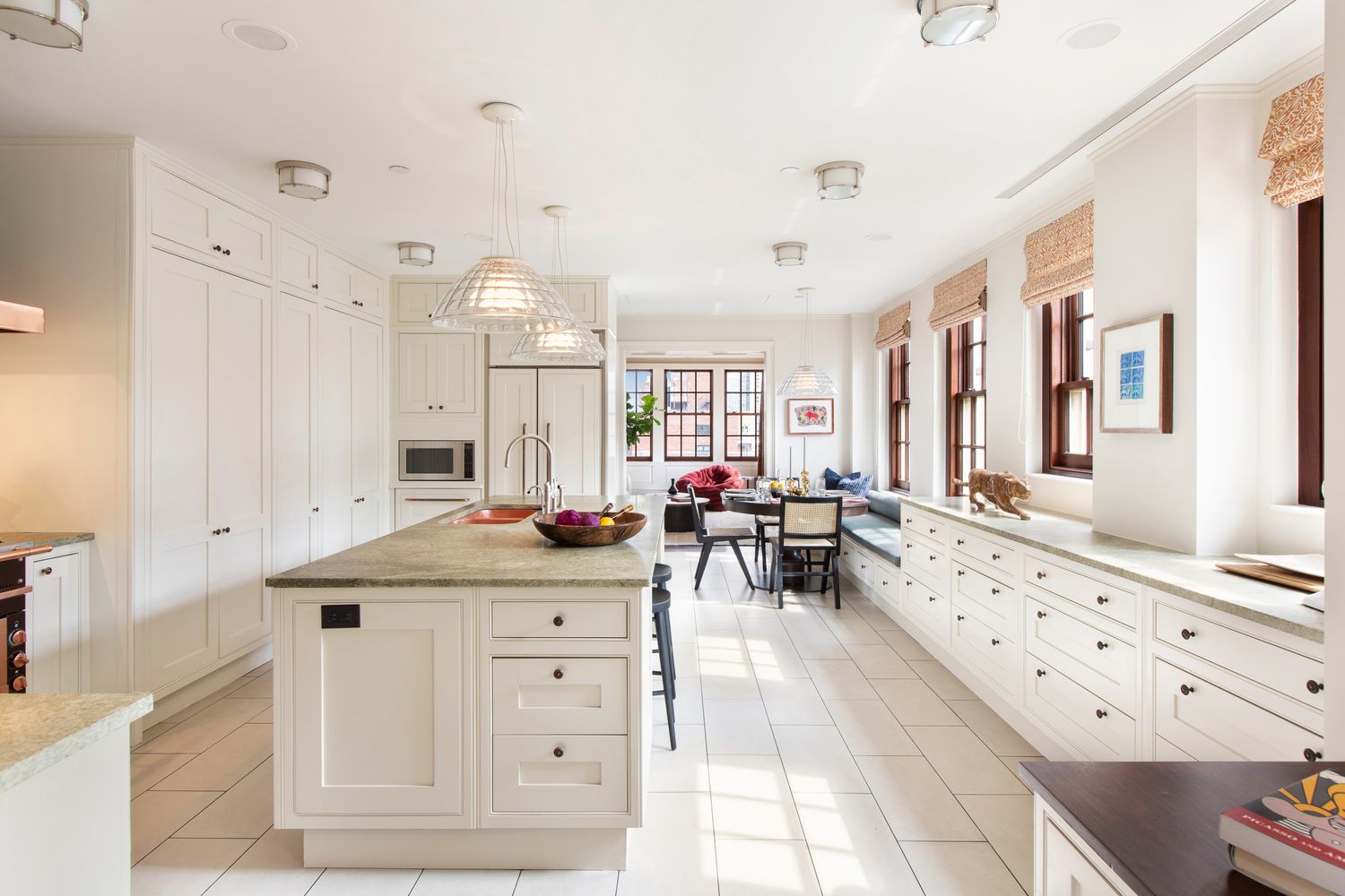 a large white kitchen with a stove a sink dishwasher and white cabinets with wooden floor