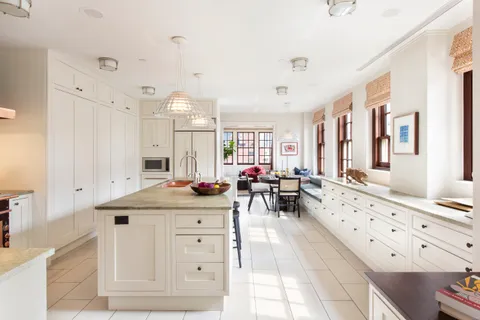 a large white kitchen with a stove a sink dishwasher and white cabinets with wooden floor