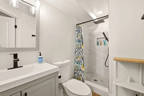 a bathroom with a sink a toilet and shower