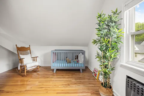 a view of a bedroom with wooden floor and a potted plant
