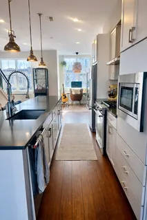 a kitchen with stainless steel appliances granite countertop a sink a stove and a wooden floors