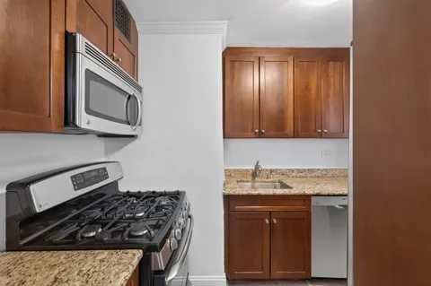 a kitchen with granite countertop stainless steel appliances a stove a microwave oven and cabinets