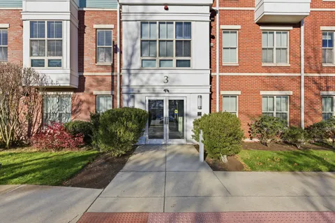 a view of a brick house with a yard and plants