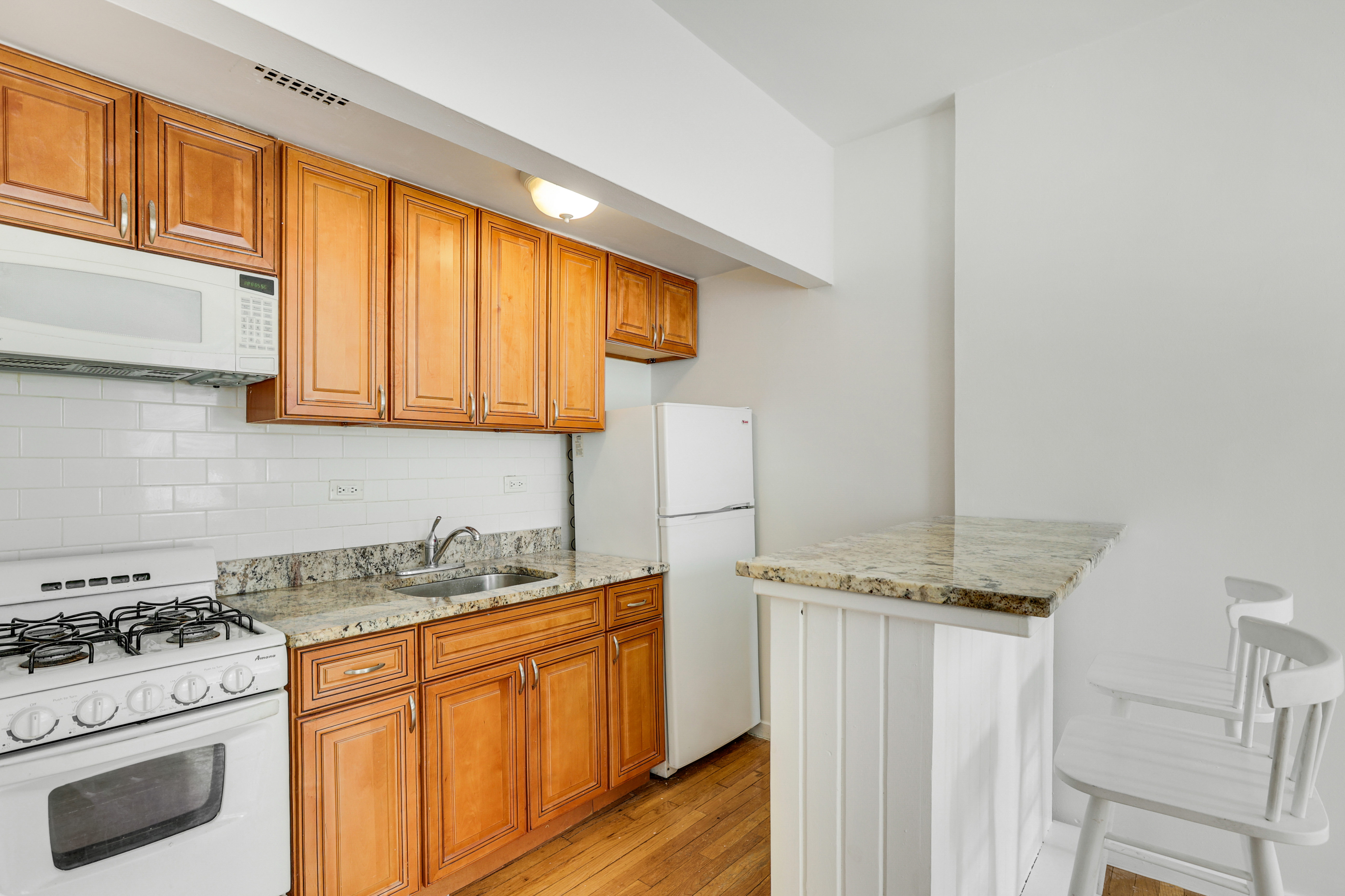 141 West 94th Street, Unit 1F Manhattan, NY 10025 - Photo 4 of 9 a kitchen with granite countertop cabinets stainless steel appliances and wooden floor