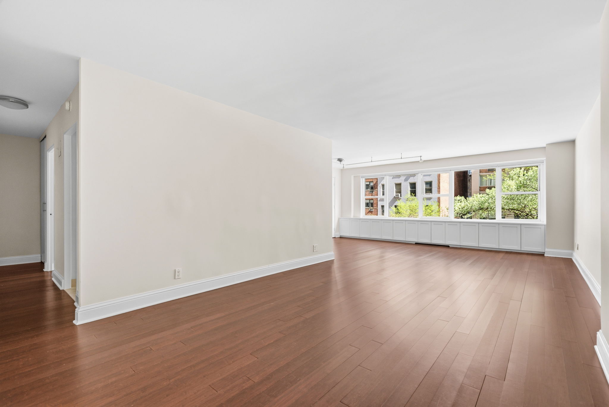 360 East 72nd Street, Unit A306 Manhattan, NY 10021 - Photo 8 of 17 an empty room with wooden floor and windows