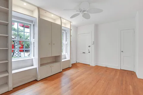 a view of empty room with wooden floor and fan