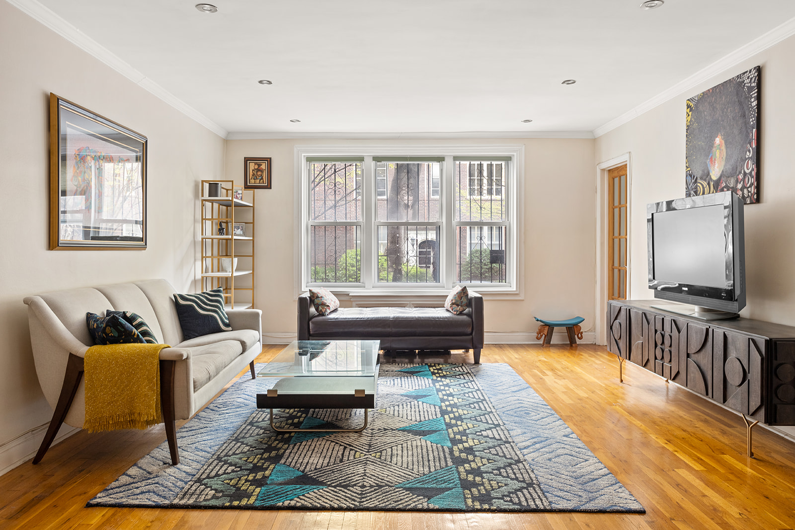 79-10 34th Avenue, Unit 2G Queens, NY 11372 - Photo 2 of 11 a living room with furniture and a flat screen tv