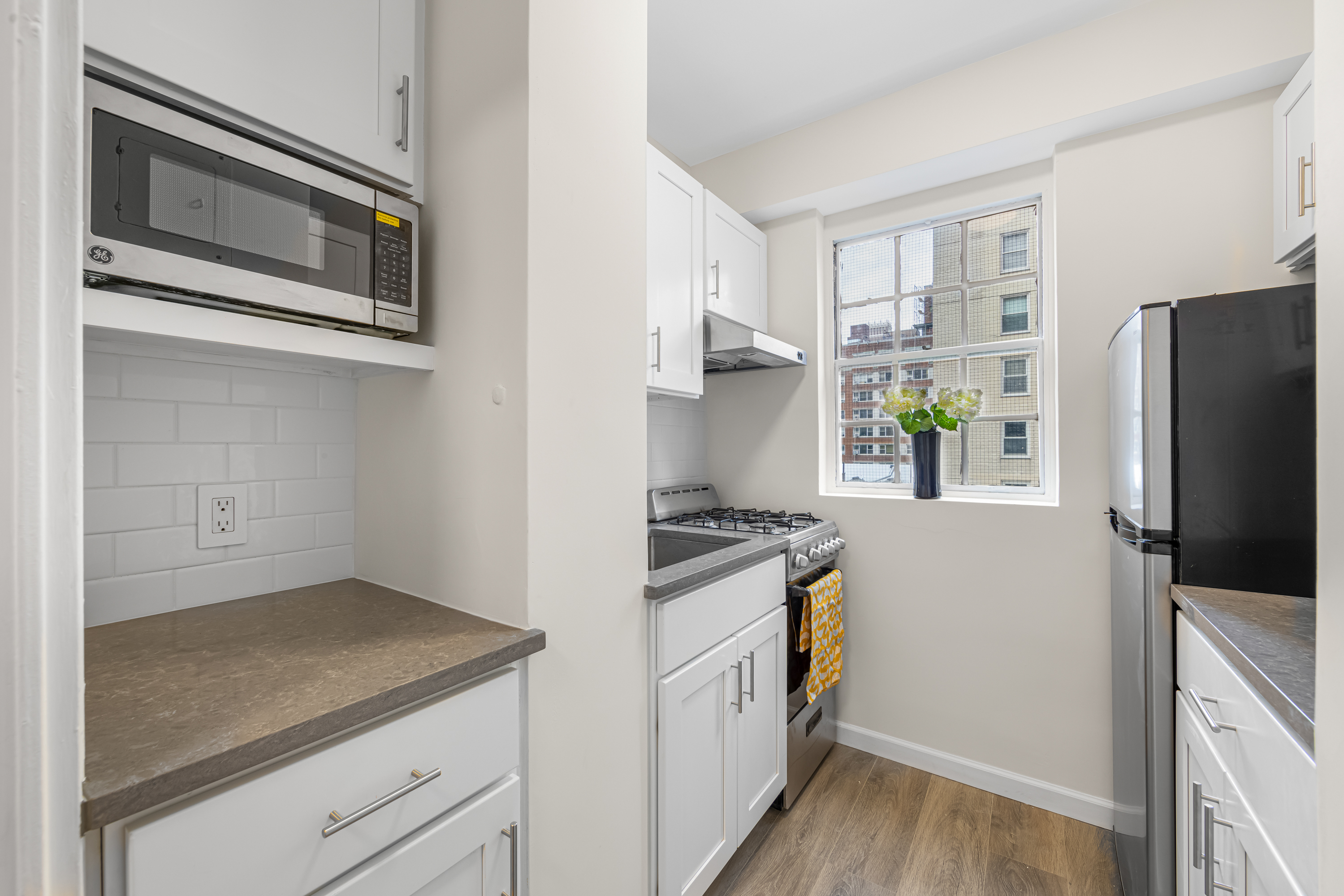 150 East 37th Street, Unit 10F Manhattan, NY 10016 - Photo 8 of 20 a kitchen with granite countertop cabinets stainless steel appliances and wooden floor