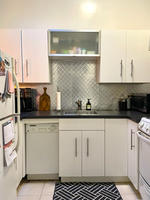 210 East 60th Street, Unit 4 Manhattan, NY 10022 - Photo 3 of 8 a kitchen with white cabinets and sink