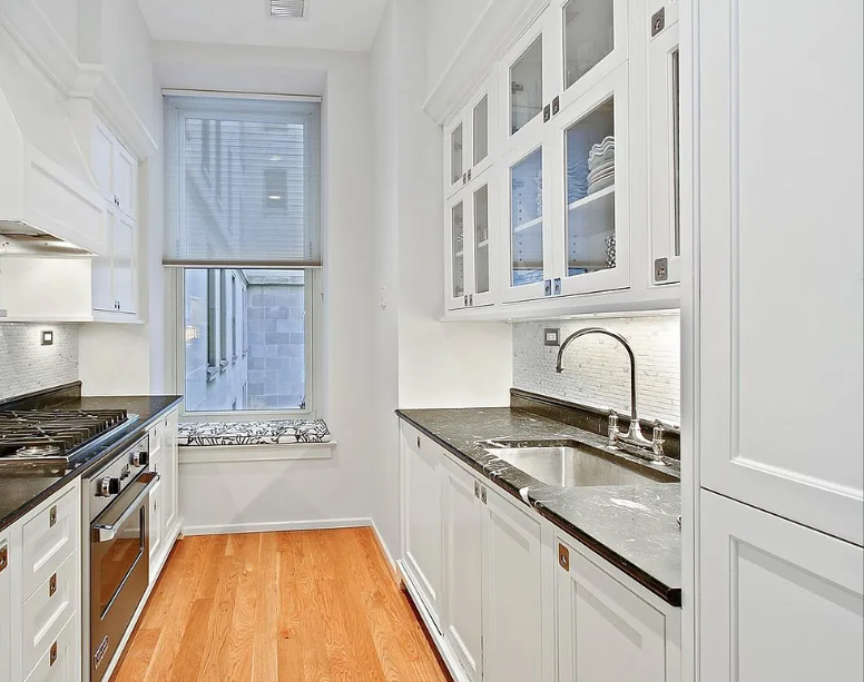 1 Central Park South, Unit 606 Manhattan, NY 10019 - Photo 8 of 13 a kitchen with granite countertop a stove a sink and a refrigerator