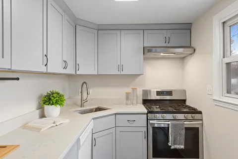 a kitchen with stainless steel appliances white cabinets and a stove top oven