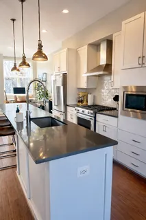 a kitchen with stainless steel appliances granite countertop a sink a stove and a wooden floors