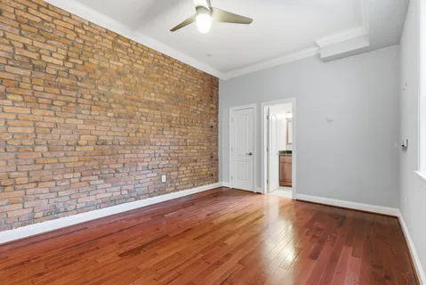 a view of an empty room with wooden floor and a ceiling fan
