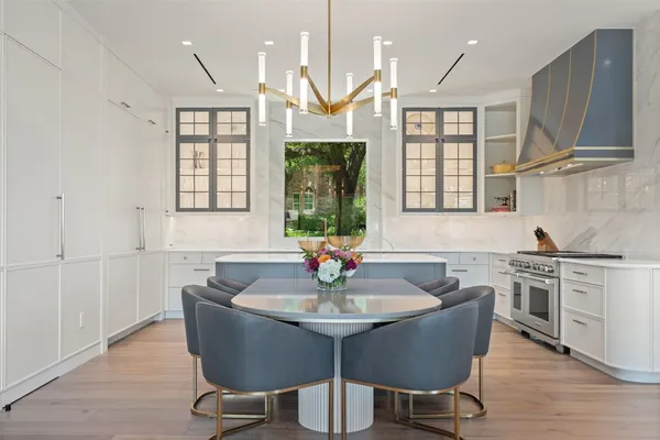 a kitchen with stainless steel appliances granite countertop a stove a sink dishwasher a dining table and chairs with wooden floor