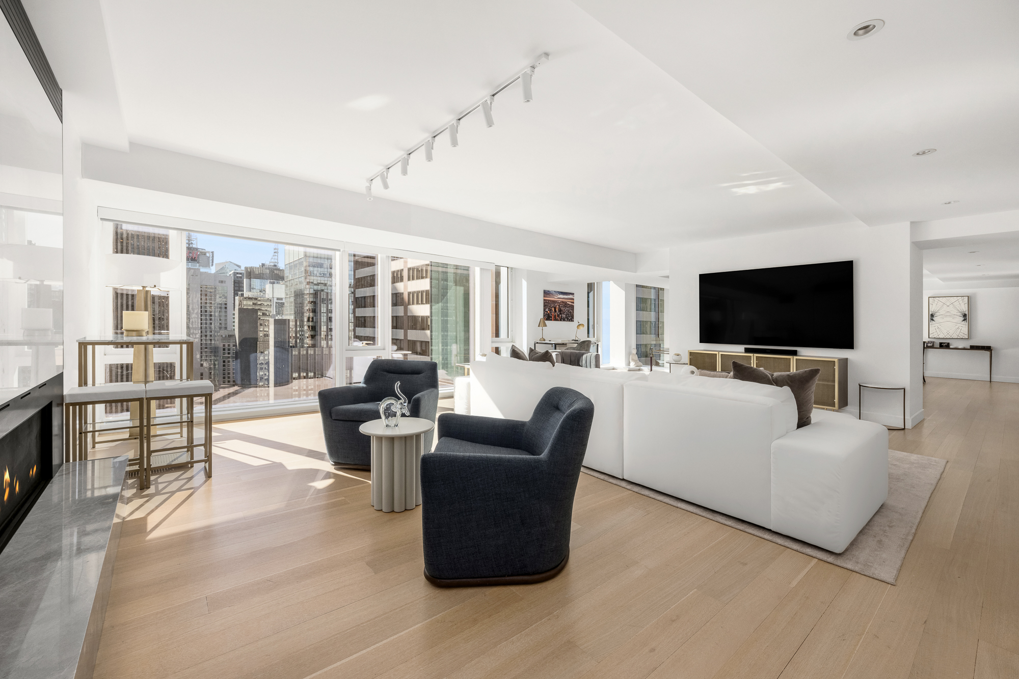 135 West 52nd Street, Unit 40A Manhattan, NY 10019 - Photo 5 of 24 a living room with furniture a flat screen tv and large window