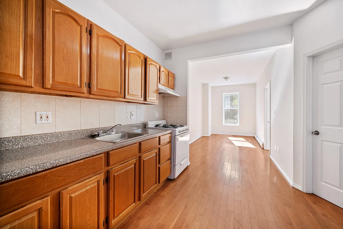 1402 Cortelyou Road, Unit 3 Brooklyn, NY 11226 - Photo 3 of 8 a kitchen with stainless steel appliances granite countertop a sink stove and wooden cabinets