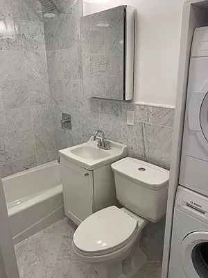 a white toilet sitting next to a bathroom sink and tub