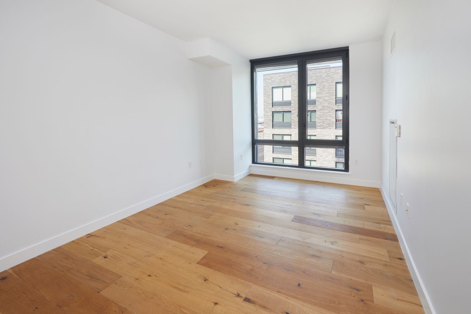 23 West 116th Street, Unit 8A Manhattan, NY 10026 - Photo 13 of 28 an empty room with wooden floor and windows