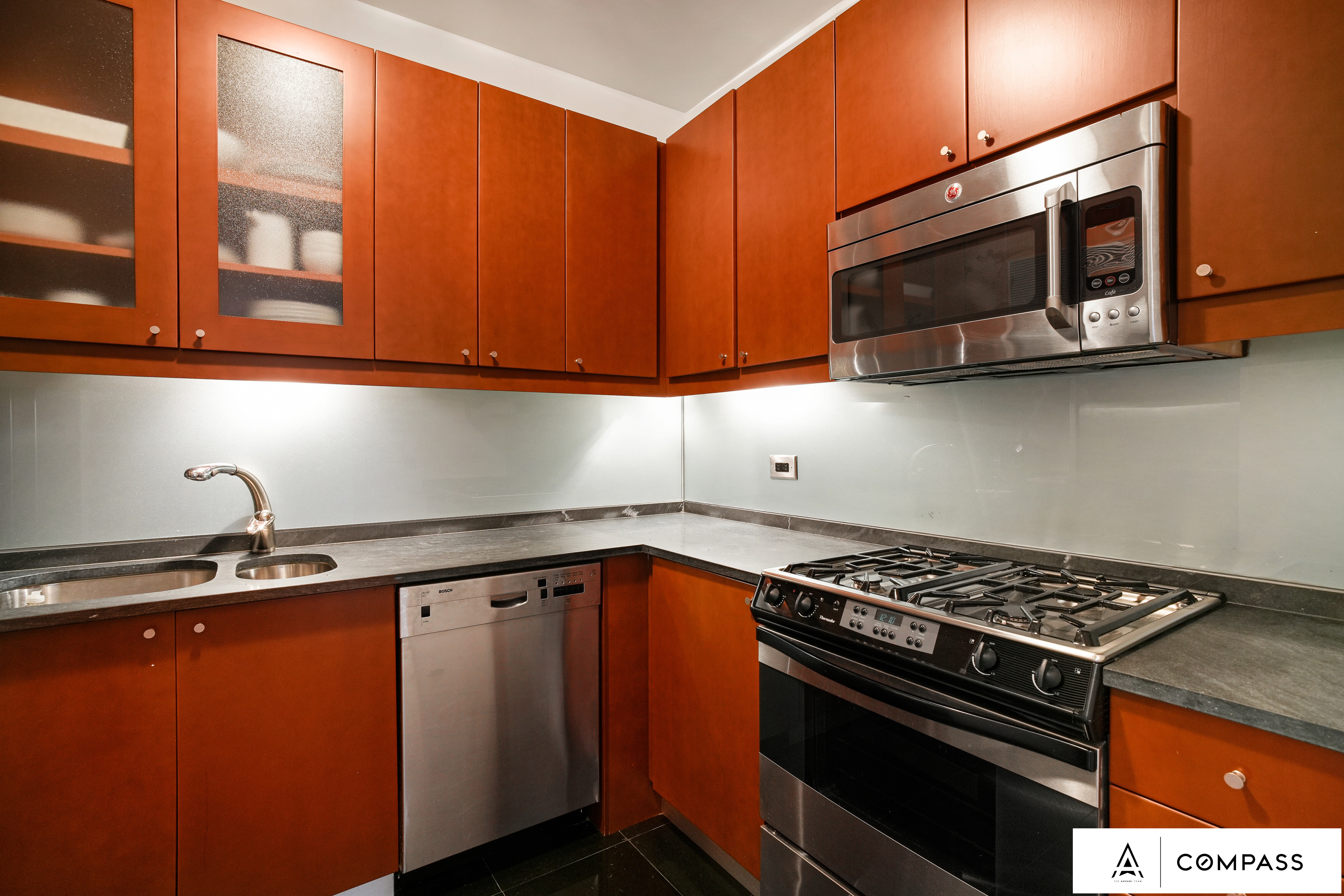 230 West 56th Street, Unit 49C Manhattan, NY 10019 - Photo 5 of 14 a kitchen with granite countertop a stove top oven microwave and cabinets