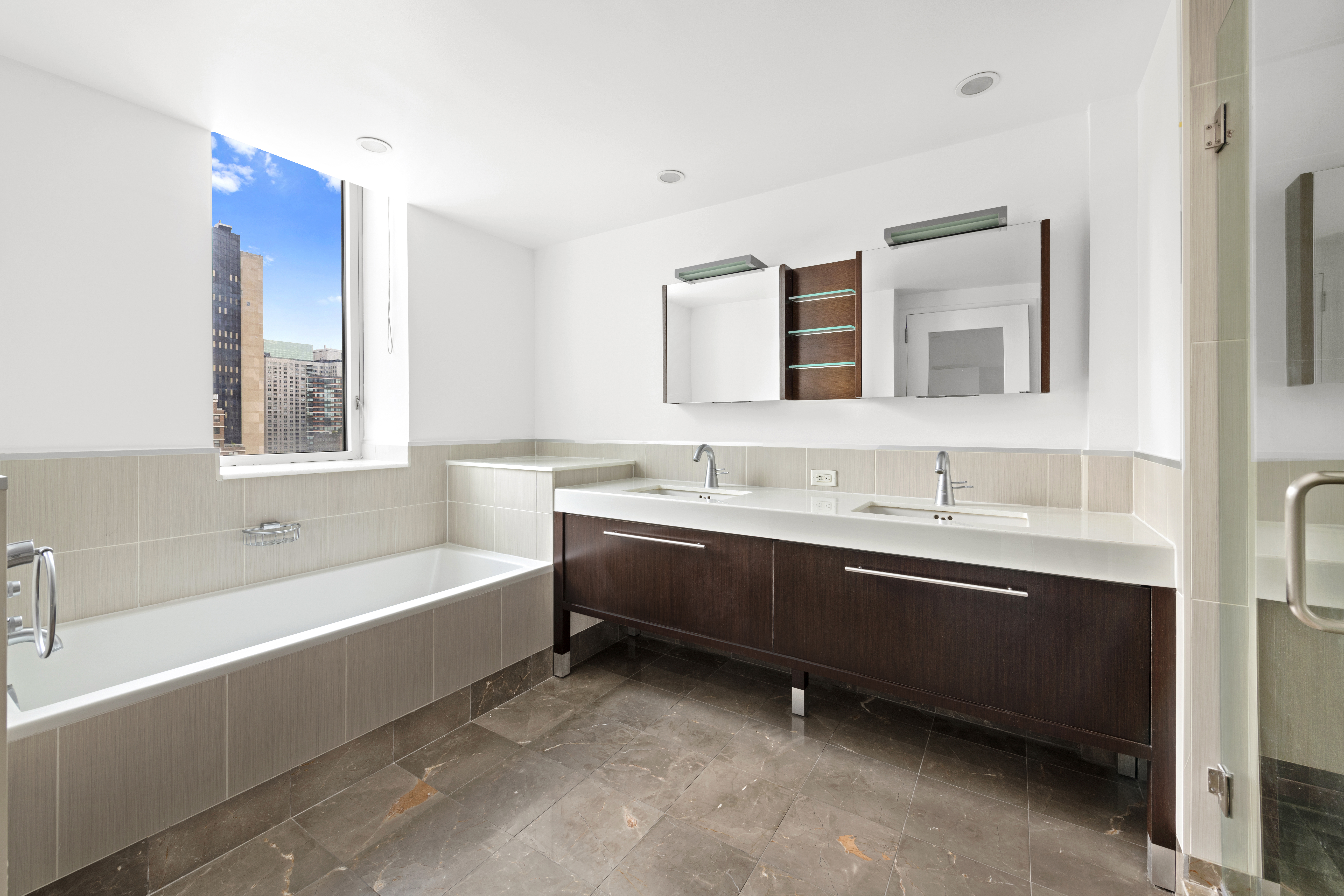 225 East 34th Street, Unit 19C Manhattan, NY 10016 - Photo 4 of 18 a bathroom with a bathtub a double vanity sink and mirror