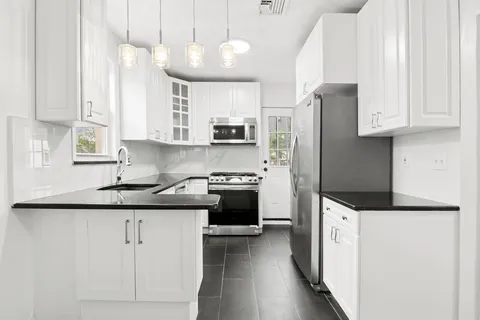 a kitchen with granite countertop a sink stove and refrigerator