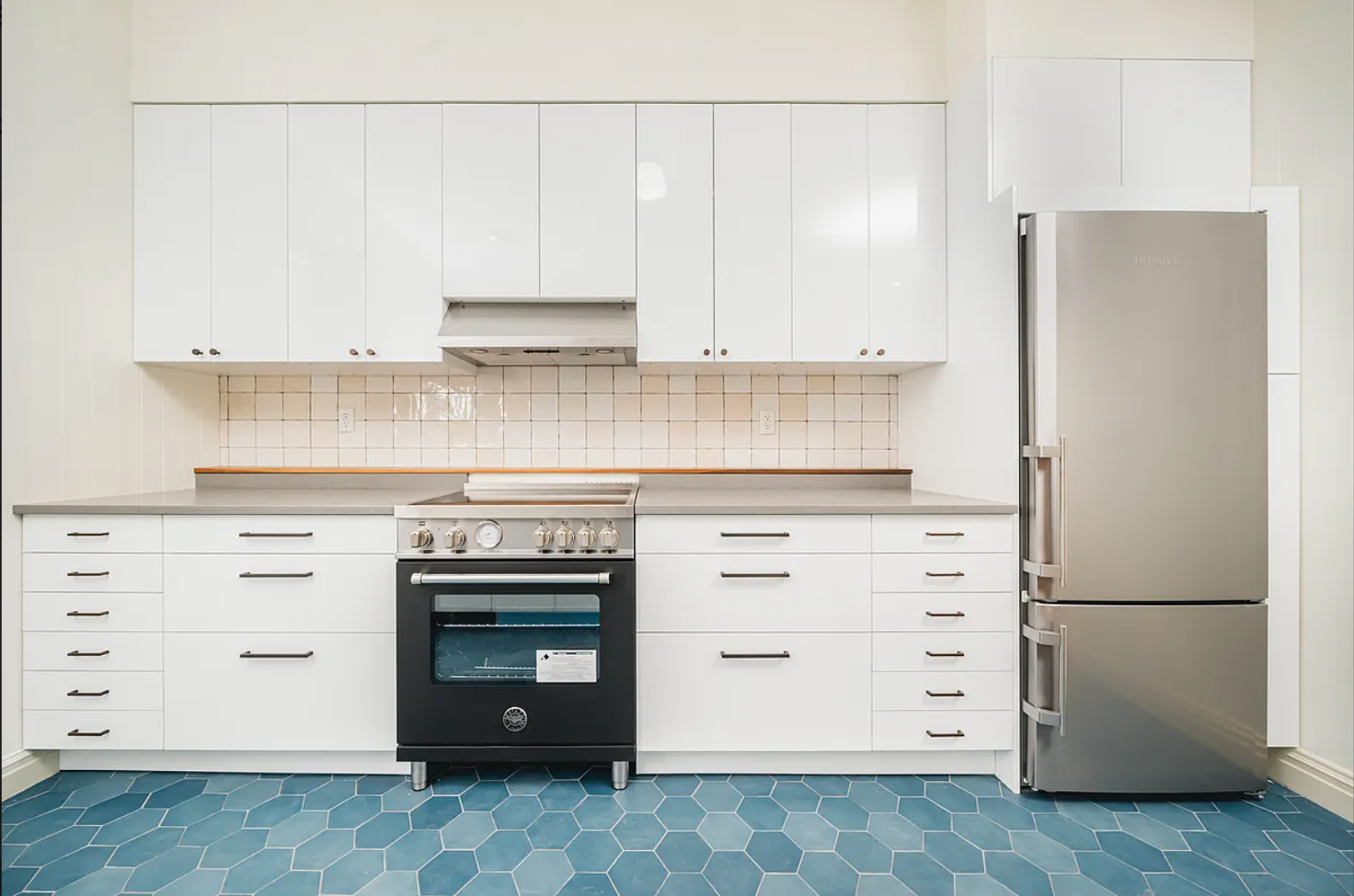 68-38 Forest Avenue, Unit 3R Queens, NY 11385 - Photo 7 of 15 a kitchen with granite countertop white cabinets and refrigerator stove