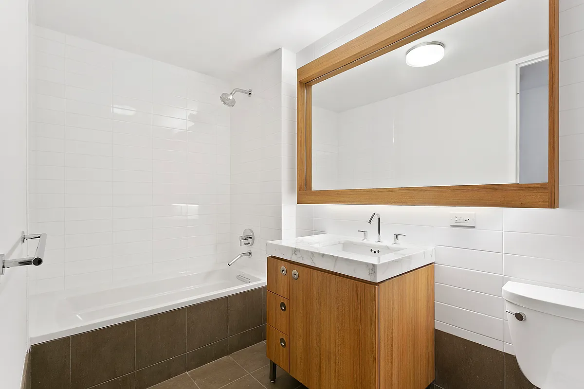 57 Reade Street, Unit 14C Manhattan, NY 10007 - Photo 12 of 16 a bathroom with a sink a toilet a mirror and shower