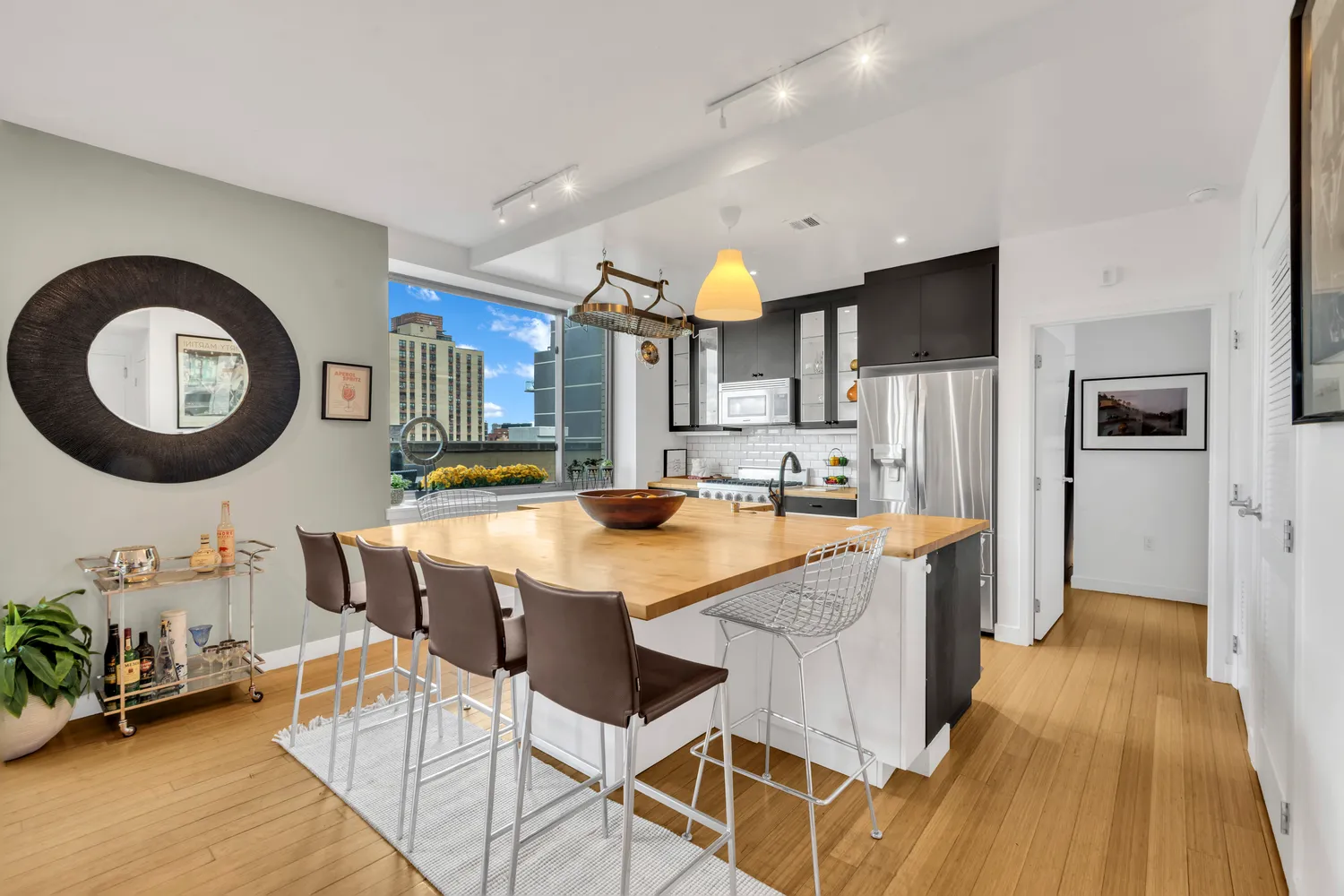 a kitchen with stainless steel appliances kitchen island granite countertop a refrigerator a stove a sink and a dining table with wooden floor