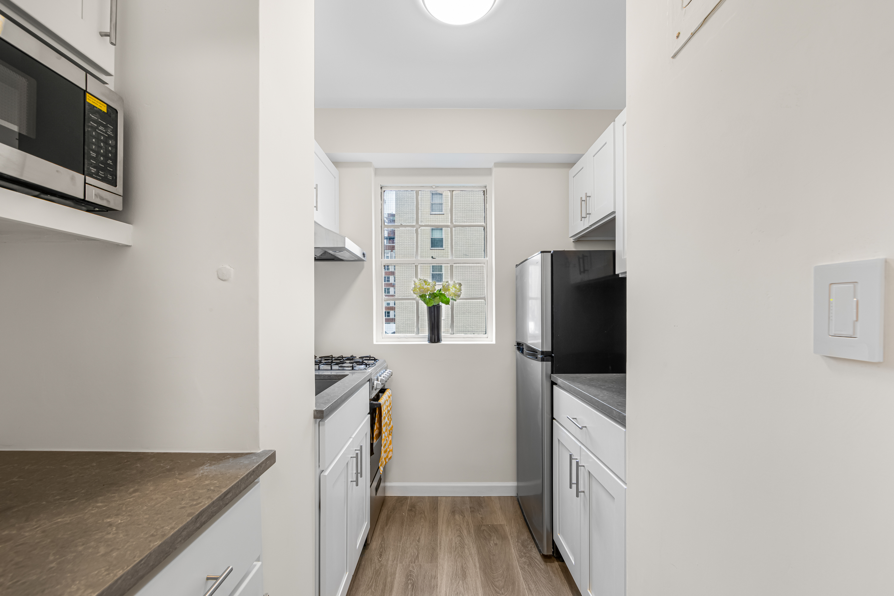 150 East 37th Street, Unit 10F Manhattan, NY 10016 - Photo 9 of 20 a kitchen with granite countertop a refrigerator stove and microwave