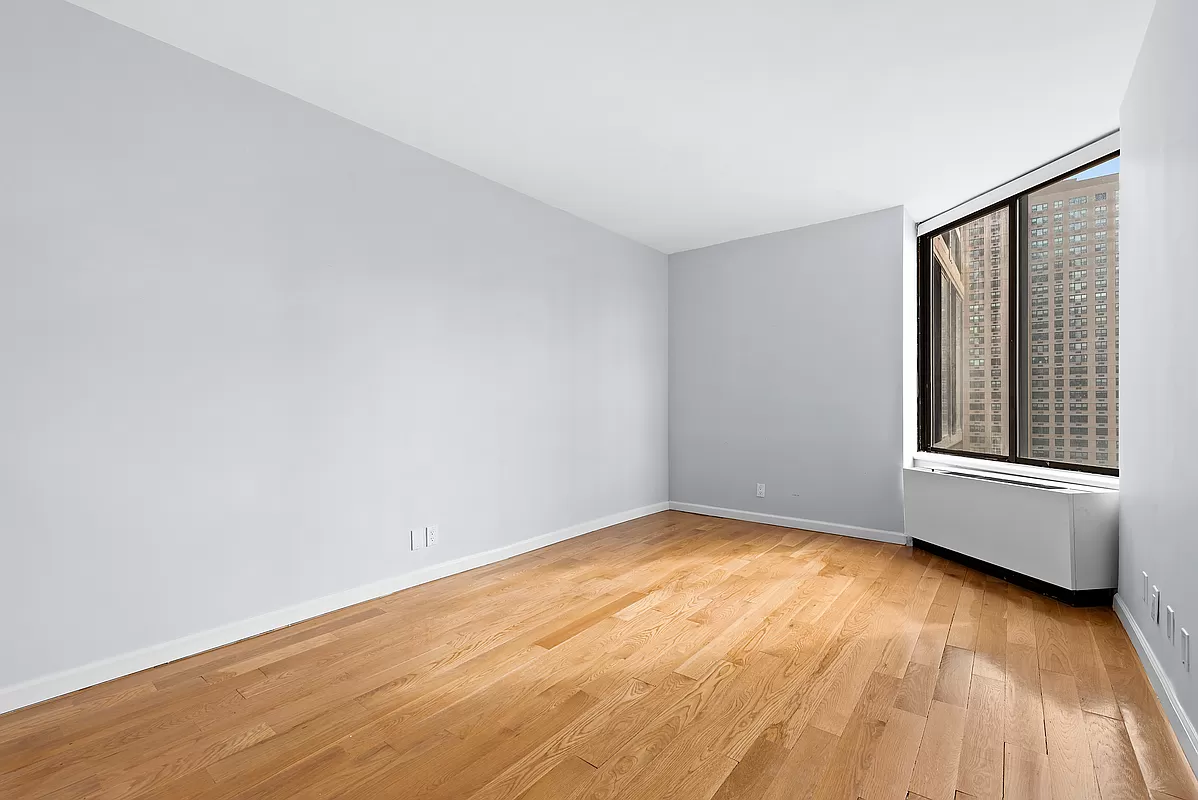 300 East 93rd Street, Unit 14F Manhattan, NY 10128 - Photo 9 of 14 a view of an empty room with wooden floor and a window
